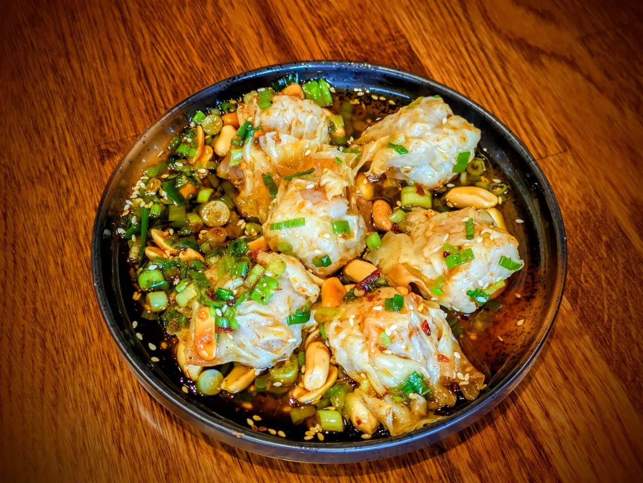 Spicy pork and shrimp wontons in lemongrass chili oil with crushed peanuts at Fire Pho in Huntington Beach, CA.